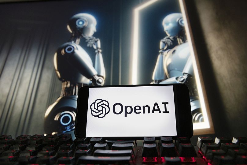 Das OpenAI-Logo auf einem Mobiltelefon mit einem Bild auf einem Computermonitor, das von ChatGPTs Dall-E Text-Bild-Modell erzeugt wurde, Freitag, 8. Dezember 2023.