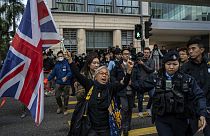 L'attivista Alexandra Wong tiene in mano una bandiera della Gran Bretagna davanti alla corte dove è previsto l'inizio del processo all'editore Jimmy Lai, a Hong Kong