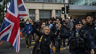 L'attivista Alexandra Wong tiene in mano una bandiera della Gran Bretagna davanti alla corte dove è previsto l'inizio del processo all'editore Jimmy Lai, a Hong Kong