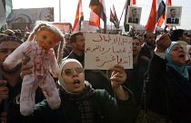 متظاهرة سورية تحمل دمية تمثل أطفال فلسطين