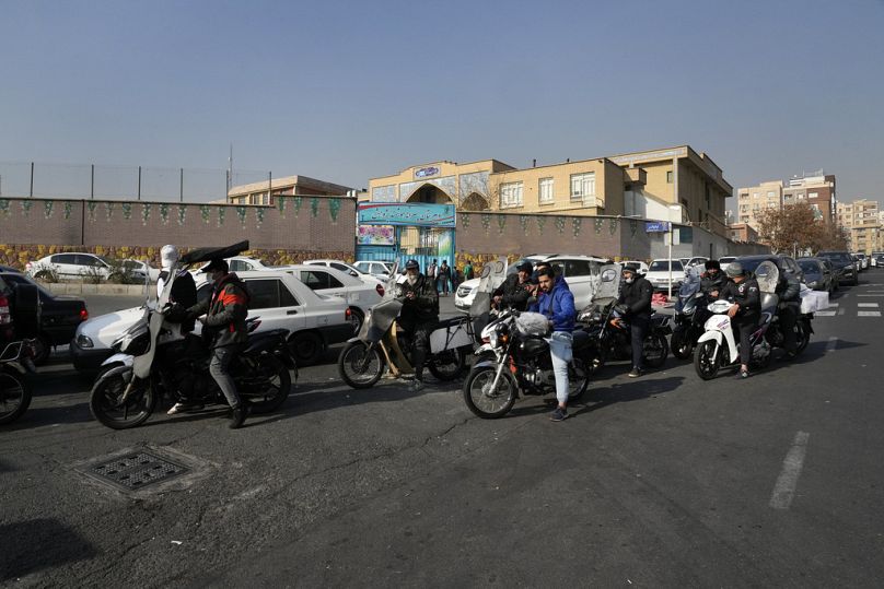 دراجات نارية وسيارات تصطف خارج محطة وقود في طهران، إيران