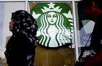 ARCHIVO - Una mujer pasa por delante de una cafetería Starbucks en Kuala Lumpur, Malasia, en julio de 2017.