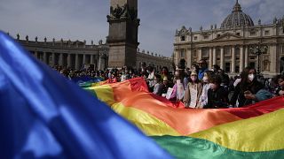 Fieles ondean una bandera arcoíris durante el ángelus en la Plaza de San Pedro en 2022