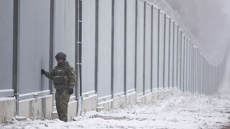Polish border guard stands next to the border wall in Nomiki, Poland, on Nov, 2022.
