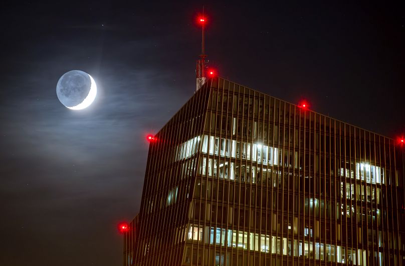 The waxing moon passes behind the European Central Bank in Frankfurt, December 2023