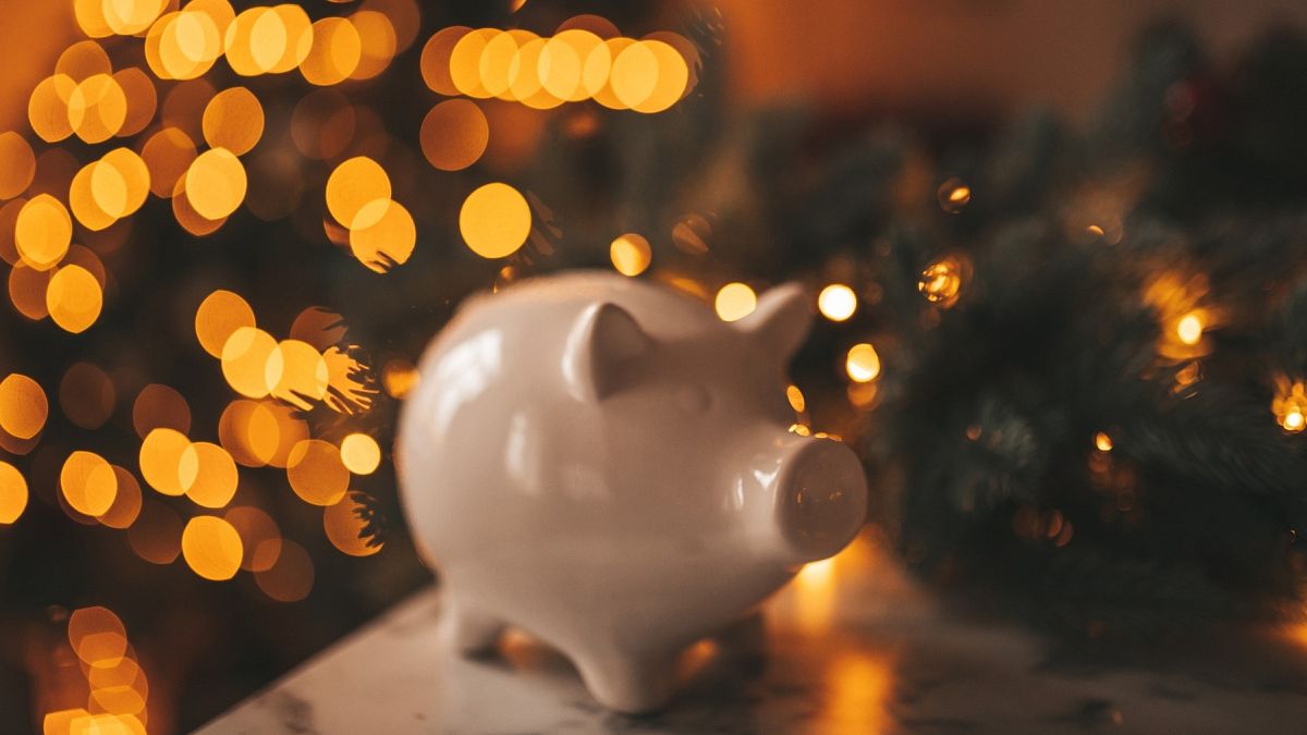 Piggy bank in front of a Christmas tree.