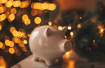Piggy bank in front of a Christmas tree.