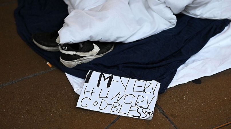 A sign reading "I'm very hungry, Godbless" is pictured at the end of a rough sleeper's makeshift bed and camps at daybreak on Oxford Street in London on August 2, 2023.