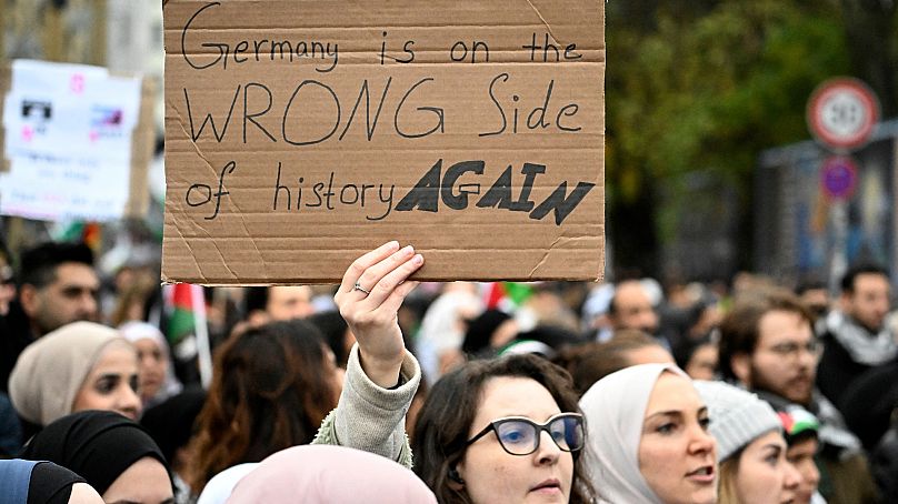 A demonstrator holds up a placard with the lettering 'Germany is on the wrong side of history again' during a rally in solidarity with Palestinians at Oranienplatz, Berlin
