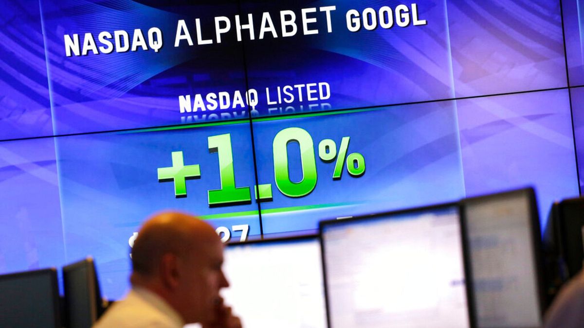 На электронных экранах отображается цена акций Alphabet.