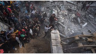 فلسطينيون يبحثون عن جثث وناجين تحت أنقاض مبنى سكني دمر في غارة جوية إسرائيلية في رفح 