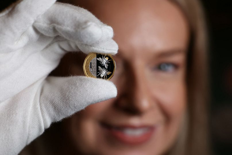 An assistant holds up a £1 coin during a photocall to unveil eight new designs that are set to appear on UK coins, at the Royal Mint, in London on October 12, 2023. Britain's