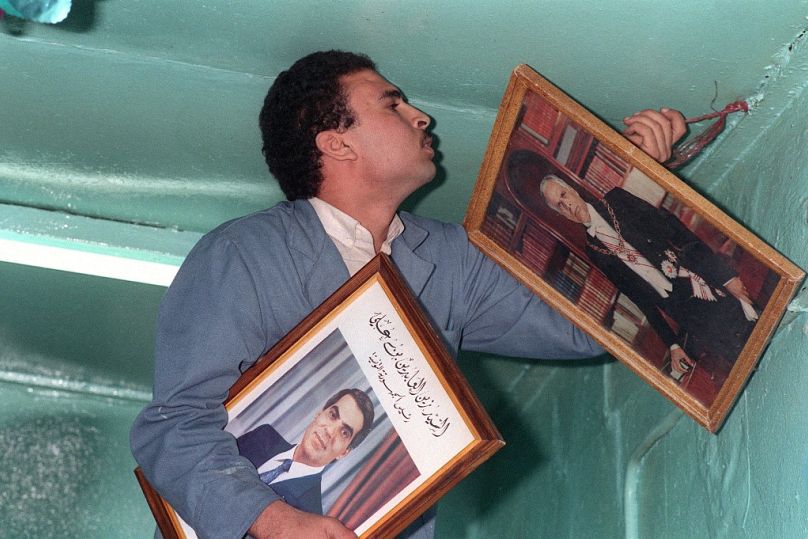 A Tunisian shop-keeper replaces the portrait of former president Habib Bourguiba with one of the new president Zine el-Abidine Ben Ali in Tunis, November 1987