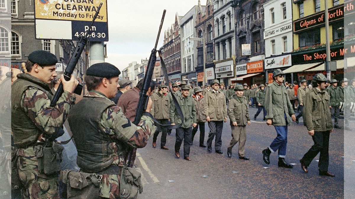 سربازان بریتانیایی نظاره گر رژه اعضای انجمن دفاع اولستر در بلفاست، ایرلند شمالی هستند، در آگوست ۱۹۷۲ 