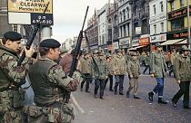 سربازان بریتانیایی نظاره گر رژه اعضای انجمن دفاع اولستر در بلفاست، ایرلند شمالی هستند، در آگوست ۱۹۷۲ 