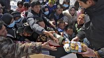 Sfollati del terremoto ricevono cibo da un volontario in un insediamento temporaneo nel villaggio di Chenjiacun, nella provincia del Gansu