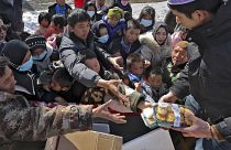 Sfollati del terremoto ricevono cibo da un volontario in un insediamento temporaneo nel villaggio di Chenjiacun, nella provincia del Gansu