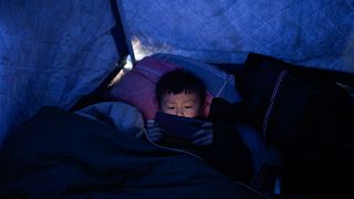 Un sobreviviente del terremoto sostiene un teléfono móvil en un refugio improvisado hecho de lona en Jishishan, en Gansu, en el noroeste de China, el 20 de diciembre de 2023.