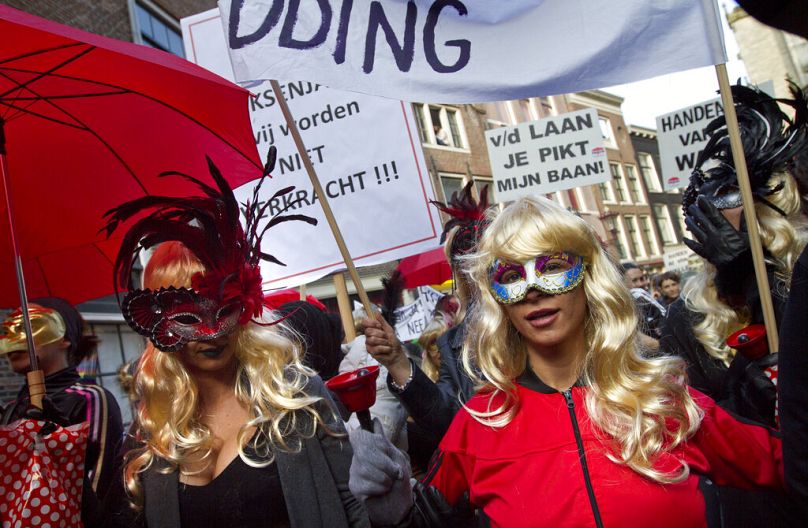 Masked women hold banners as prostitutes and sympathisers take to the streets to protest plans to clean up the city's famed red light district.