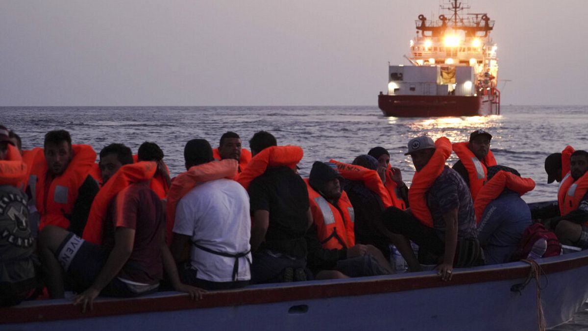 Migrants on an overcrowded wooden boat wait to be rescued in the Mediterranean Sea