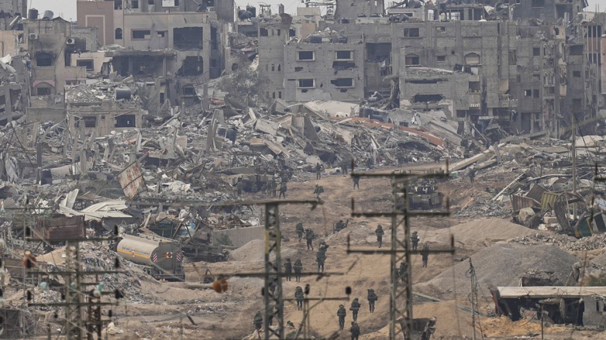 Israeli troops walk in the Gaza Strip as seen from southern Israel, Thursday, Dec. 21, 2023.