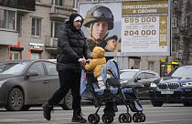 A man and his child pass an army recruitment poster in Moscow 