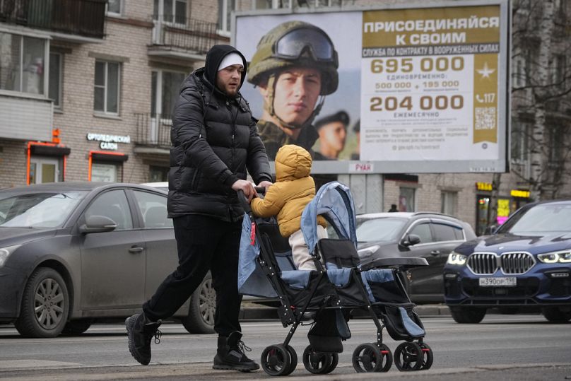 Мужчина проходит мимо рекламного щита, рекламирующего военную службу по контракту в российской армии. Санкт-Петербург, ноябрь 2023 года.