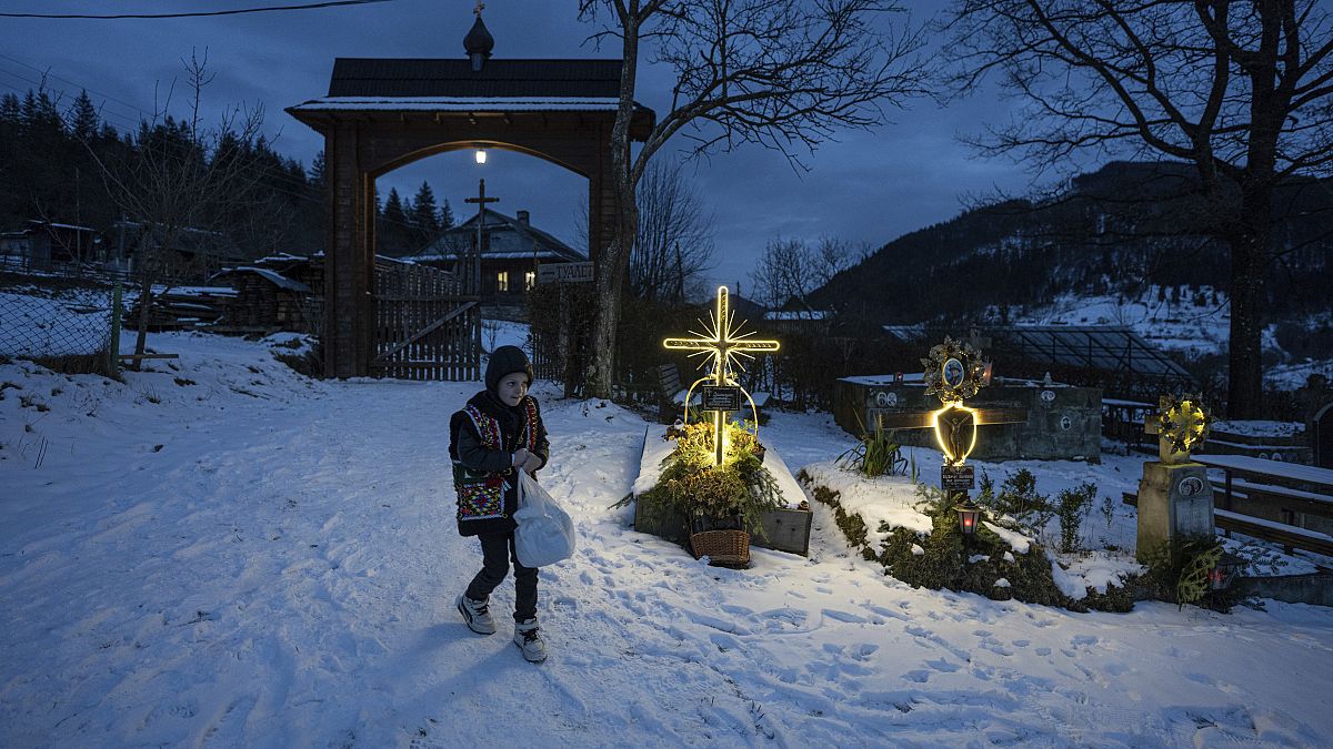 Um menino caminha num cemitério após as celebrações de Natal na igreja da aldeia de Kryvorivnia, Ucrânia, em 24 de dezembro 