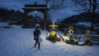 Um menino caminha num cemitério após as celebrações de Natal na igreja da aldeia de Kryvorivnia, Ucrânia, em 24 de dezembro 