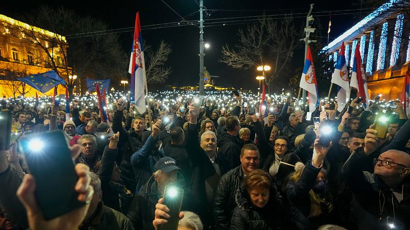 Serbian opposition supporters hold up lights during a protest outside the electoral commission building in Belgrade