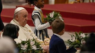 Папа римский Франциск держит статую младенца Иисуса во время рождественской мессы в соборе Святого Петра в Ватикане.