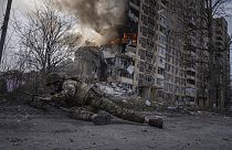 Un policía ucraniano se pone a cubierto frente a un edificio en llamas alcanzado por un ataque aéreo ruso en Avdivka, Ucrania.