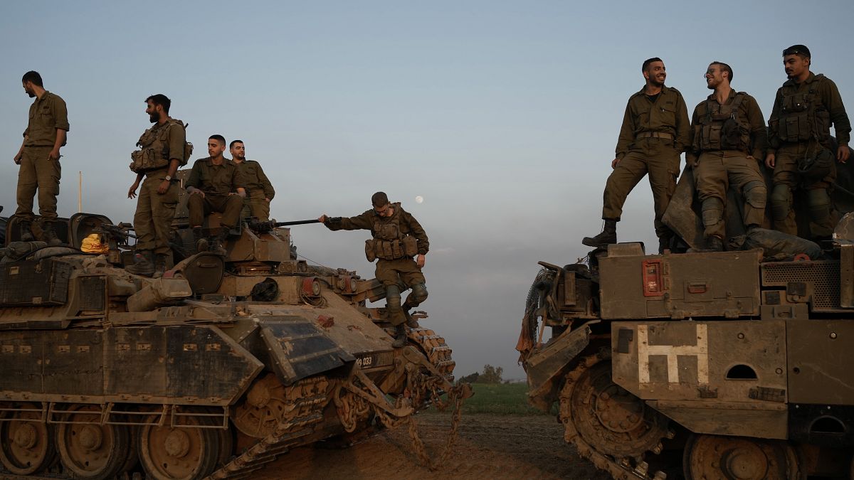 جنود إسرائيليون يقفون فوق ناقلات جند مدرعة بالقرب من الحدود بين إسرائيل وغزة، في جنوب إسرائيل
