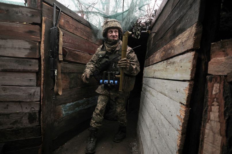 A Ukrainian serviceman holds a periscope at his position on the frontline with Russian-backed seperatists near the small city of Marinka, Donetsk region, on April 20, 2021.