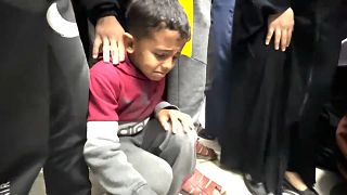 طفل يجلس قرب جثمان أحد افراد عائلته في خان يونس. 2023/12/26