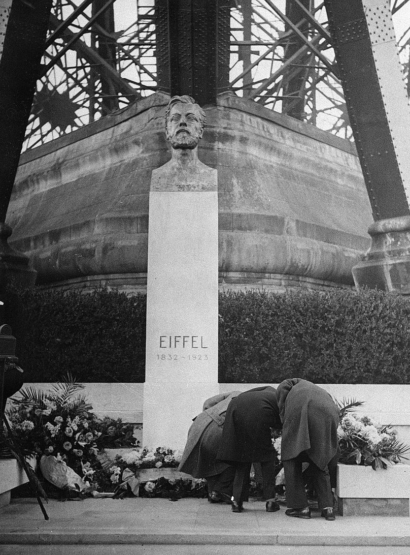 Unidentified relatives of the French engineer Gustave Eiffel place flowers at his statue in front of the Eiffel Tower in Paris - 15 Dec. 1932.