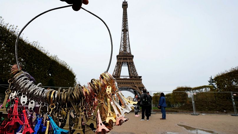 A souvenir vendor sells to tourists in front of the Eiffel Tower