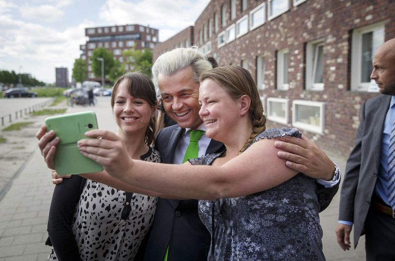 Geert Wilders, leader of the Dutch Party for Freedom, poses for a selfie with supporters as his bodyguard stand watch after casting his vote in The Hague, May 2014