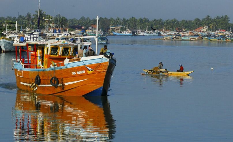 Sri Lankan fishermen stand on a fishing vessel as it leaves a fishery harbour in Negombo, outskirts of Colombo, October 2014