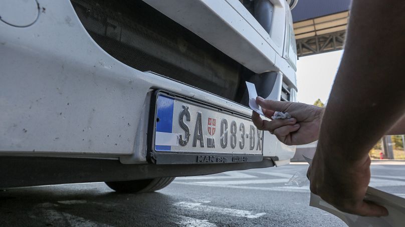 Сербский водитель заклеивает символику Сербии на своем номерном знаке, октябрь 2021 года