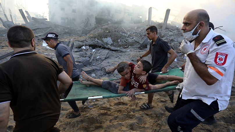 Palestinians evacuate two wounded boys following Israeli airstrikes on Gaza City, October 25