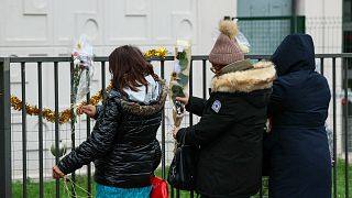 يضع الناس الزهور أمام شقة الطابق الأرضي حيث تم اكتشاف جثث امرأة وأطفالها الأربعة، في مو، شرق باريس، في 26 دجنبر 2023.