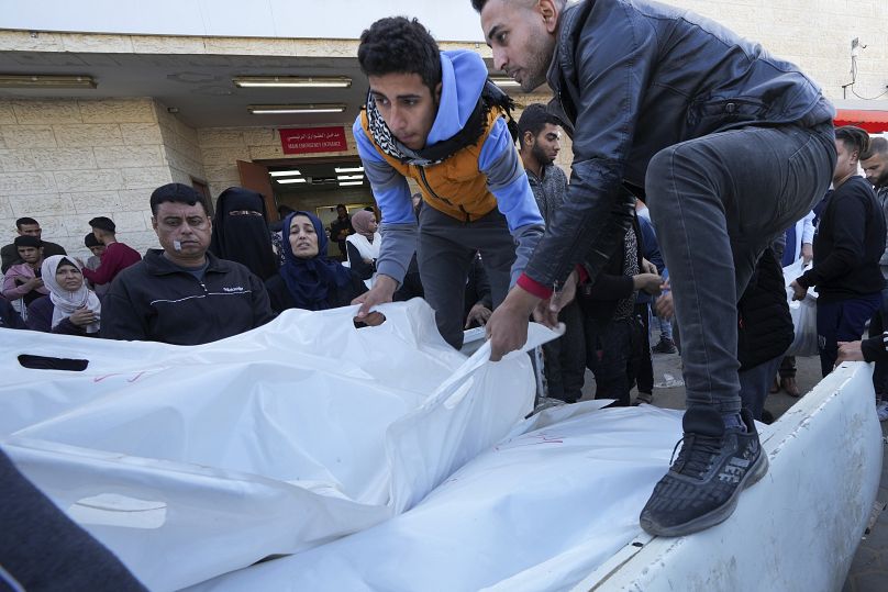 Палестинцы грузят тела своих родственников, погибших в результате израильской бомбардировки сектора Газа, на грузовик в Дейр-эль-Балахе, сектор Газа, 31 декабря 2023 года