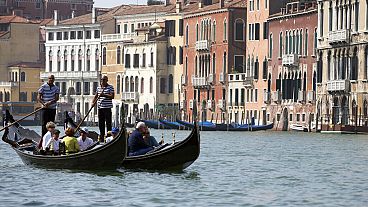 Tourists tour the Grand Canal on traditional Gondola Venetian boats, in Venice, Italy