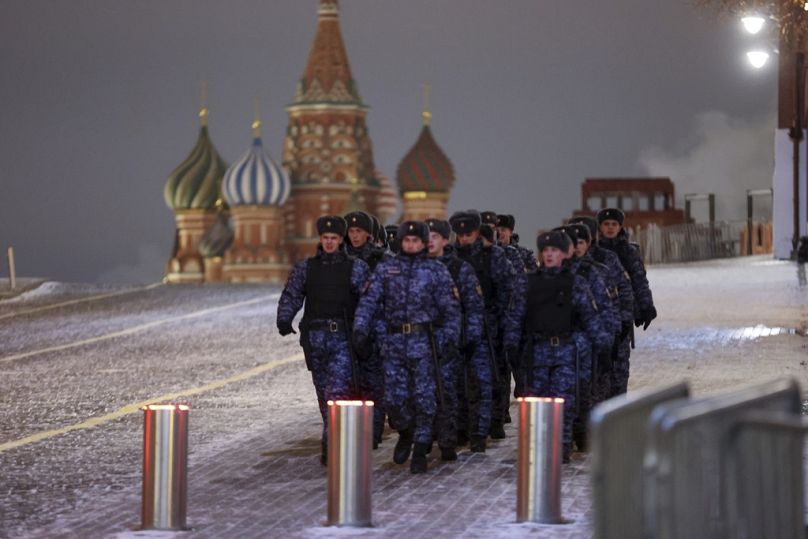 Police and the Rosguardia (National Guard) servicemen walk on the Red Square with the St. Basil's Cathedral in the background in Moscow, Russia, Sunday, Dec. 31, 2023.