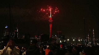 Ciudadanos neozelandeses observan el espectáculo pirotécnico en la torre Sky, con el que Auckland ha dado la bienvenida a 2024.