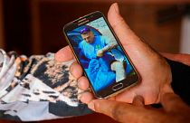 پدر سانتیاگو سانچز کوگدور عکس پسرش را بر روی موبایلش نشان می‌دهد