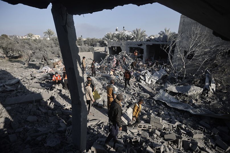 Palestinians inspect the damage of a destroyed house following Israeli airstrikes on Khan Younis, Southern Gaza Strip, Sunday, Dec. 31, 2023.