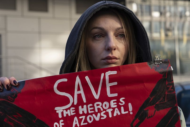 Una donna regge un manifesto con lo slogan "Salvate gli eroi di Azovstal" durante una manifestazione di protesta nel centro di Kiev, in Ucraina, domenica 31 dicembre 2023