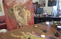 Designer and traditional dyer Claudio Cutuli holds up a finished scarf reproducing an ancient Roman fresco of intertwining Perseus and Andromeda surrounded in a Pompeii red. 